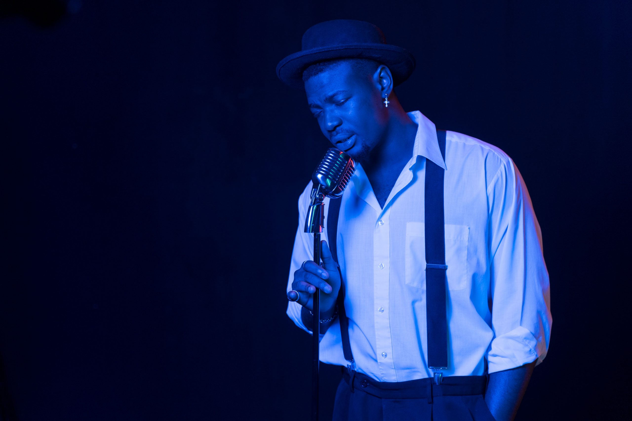 Musician in blue lighting singing into a microphone