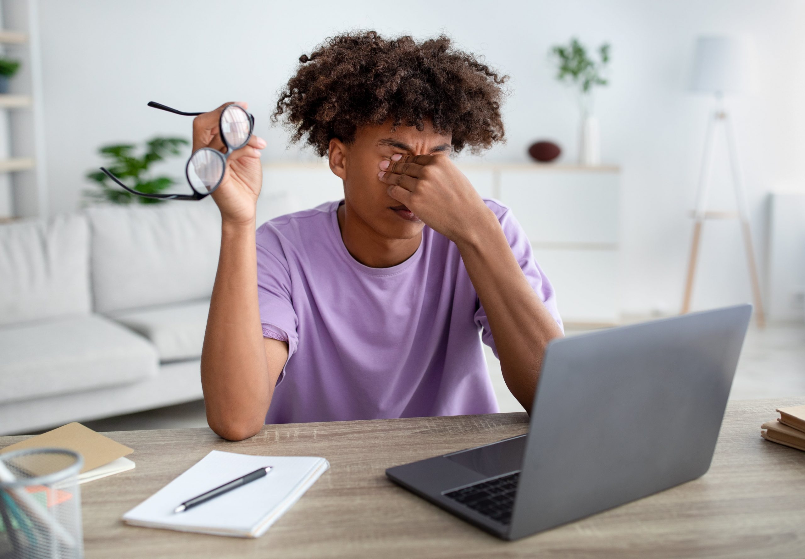 teen-guy-rubbing-tired-eyes-sitting-at-desk